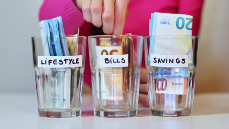 euro banknotes pulled from bills jar in slow motion by woman in bright pink top