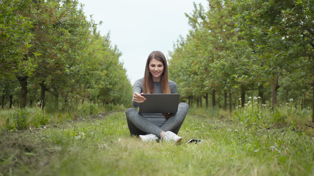 mujer trabajando en una computadora portátil en un huerto de manzanas