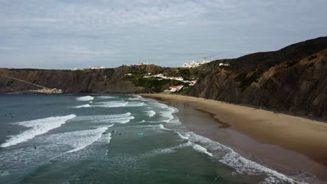 Pulling-in-drone-shot-of-the-beach-of-Arrifana-in-Portugal,-Algarve