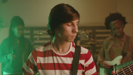 portrait of a boy playing guitar during a band rehearsal in recording studio