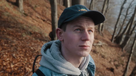 young man looking around, exploring the hilly forest on a sunny autumn day