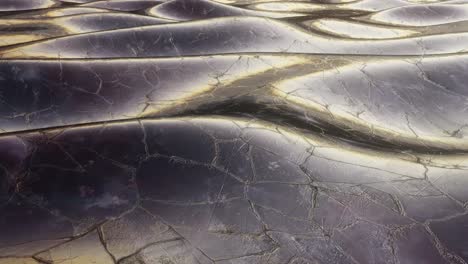 Frozen-silver-liquid-metal-waves-rolling-past,-alien-like-strange-abstract-seamless-looping-background