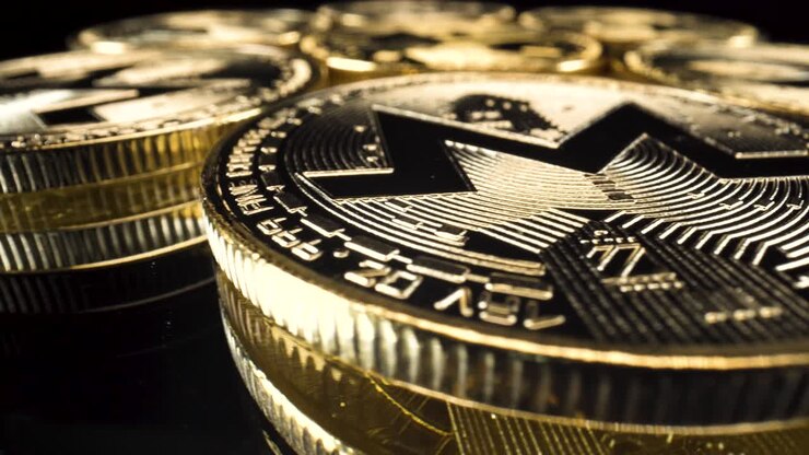 Wide-angle macro view golden monero coins turning around on reflective black glass surface, cryptocurrency investment altcoin 4k