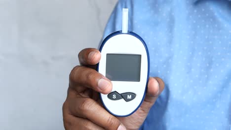 persona que sostiene un medidor de glucosa en la sangre