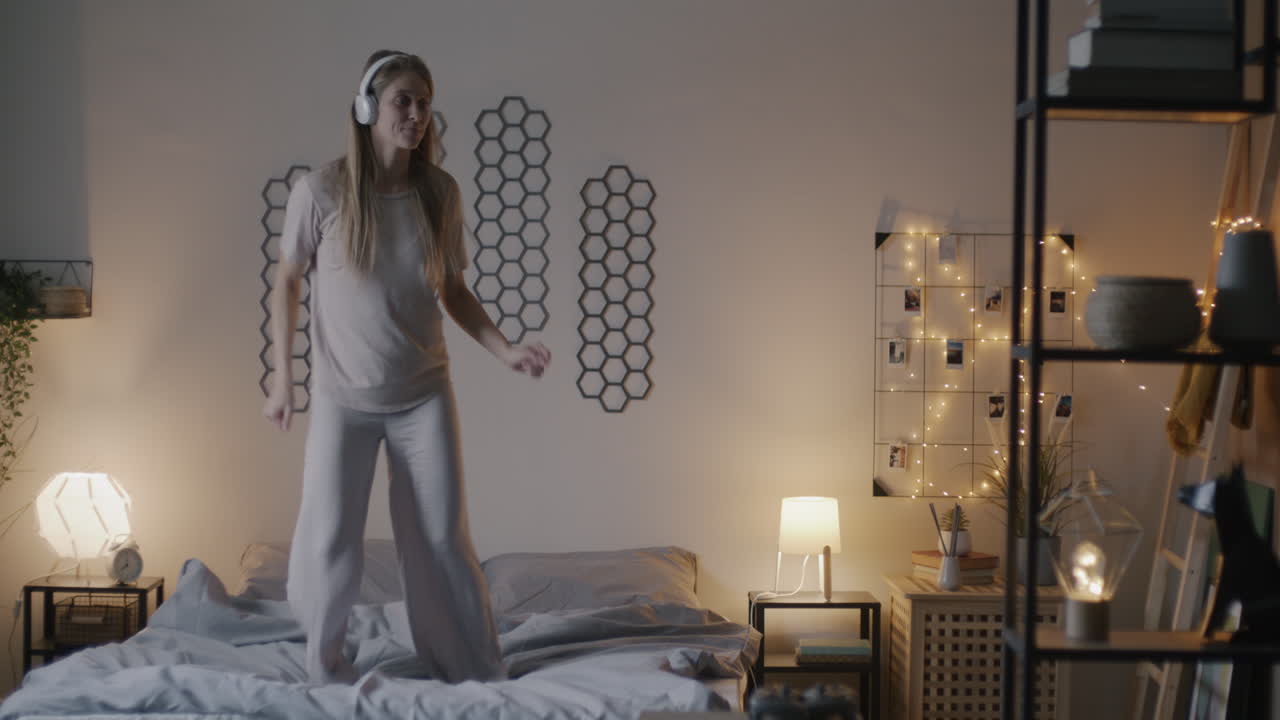 Woman dancing on bed with headphones