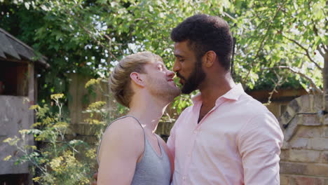 portrait of loving male gay couple at home in garden against flaring sun together