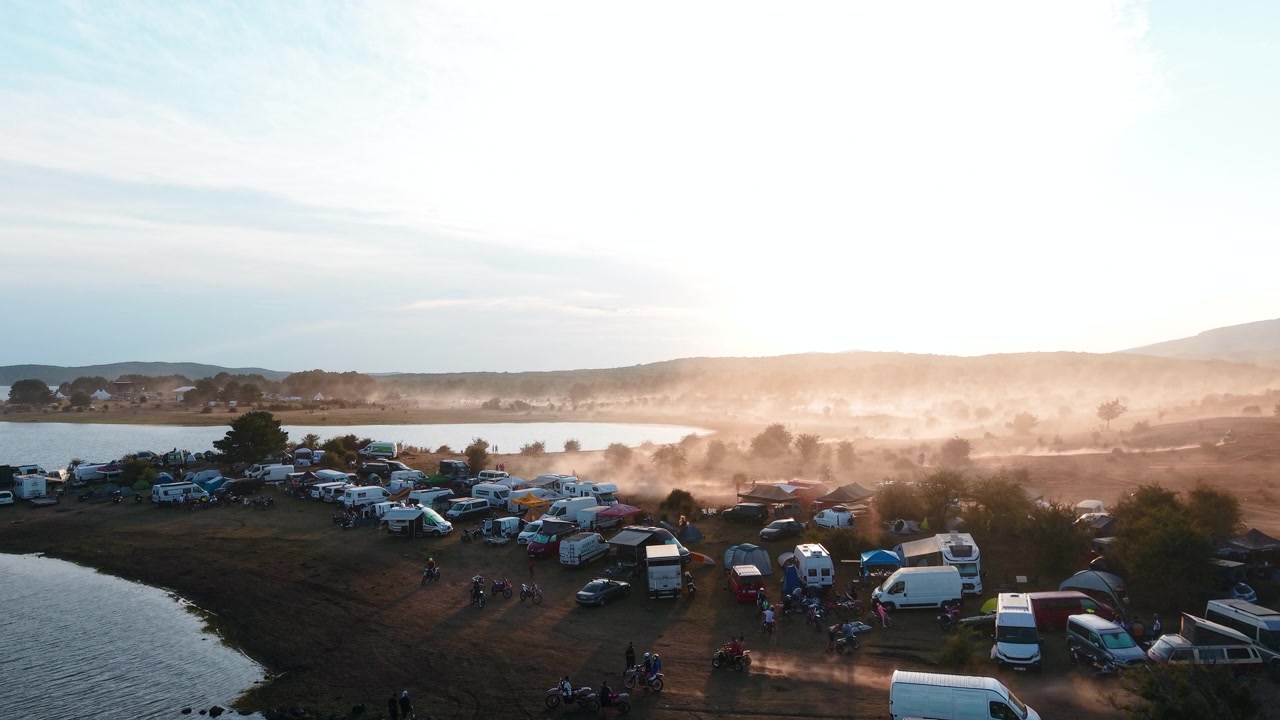 Aerial View of a Busy Campsite by a Lake at Sunrise