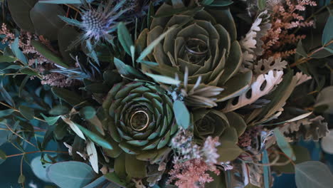 primer plano de un bouquet de novia ecléctico con anillos de bodas