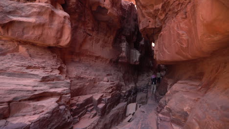 hombre caminando en el cañón de la ranura entre escarpados acantilados de arenisca en el desierto, wadi rum, jordania, incline hacia abajo revelando una vista amplia