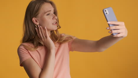 una mujer caucásica tomando selfies con su teléfono inteligente.