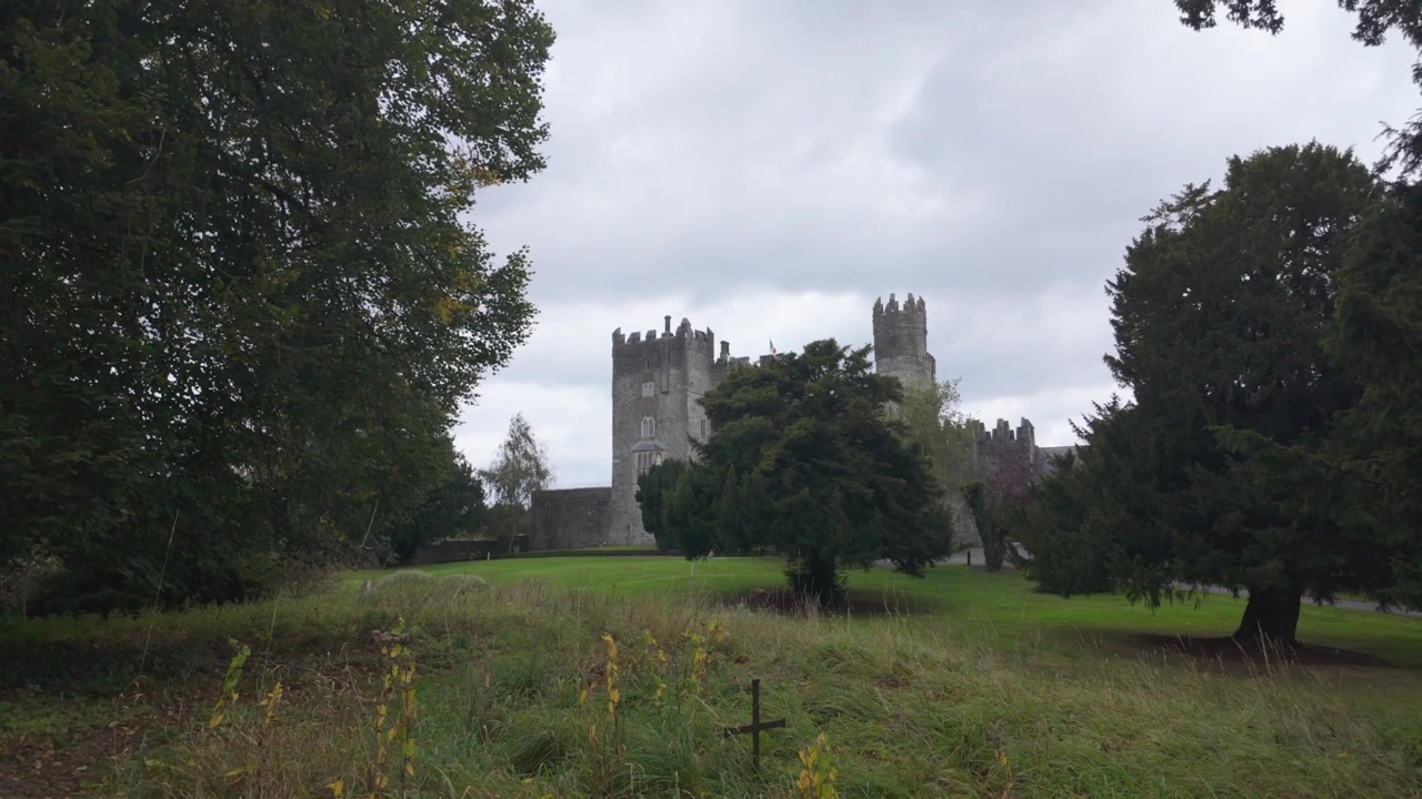 Castello irlandese ai margini del bosco, vista da un cimitero in una mattina d'autunno