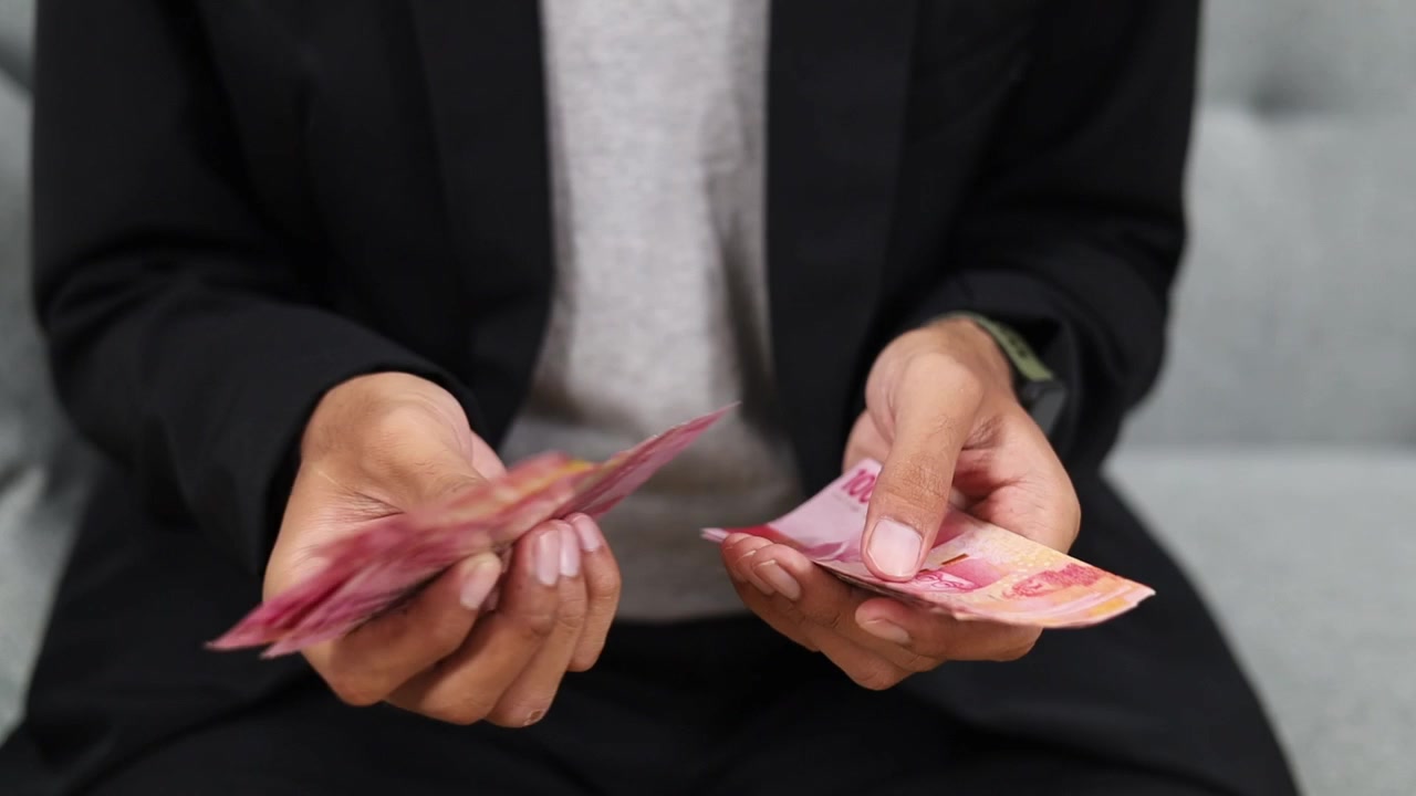 A businessman is counting Indonesia paper money hundreds of thousands of rupiah. Indonesian cash money in male hand. Close up