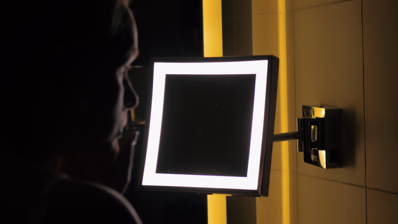 mujer mirando el espejo del baño y aplicando crema nocturna