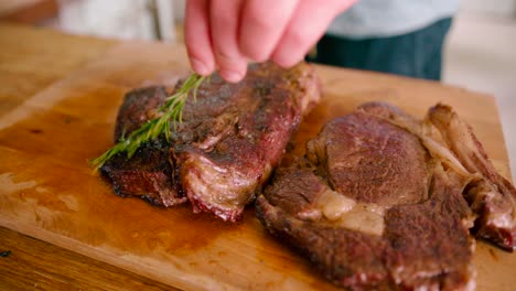 close up view of a man applying ghee to the roasted grilled steaks on the wooden table