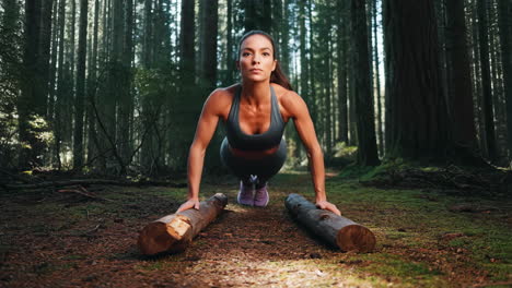 woman doing push-ups on logs in a forest