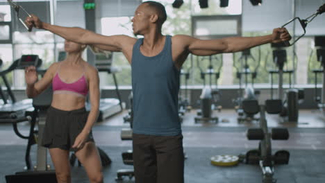 Front-view-of-caucasian-female-monitor-and-an-athletic-african-american-man-in-the-gym.