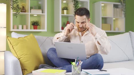 Man-working-from-home-concentrates-on-his-work,-puts-on-his-glasses-and-starts-taking-notes.