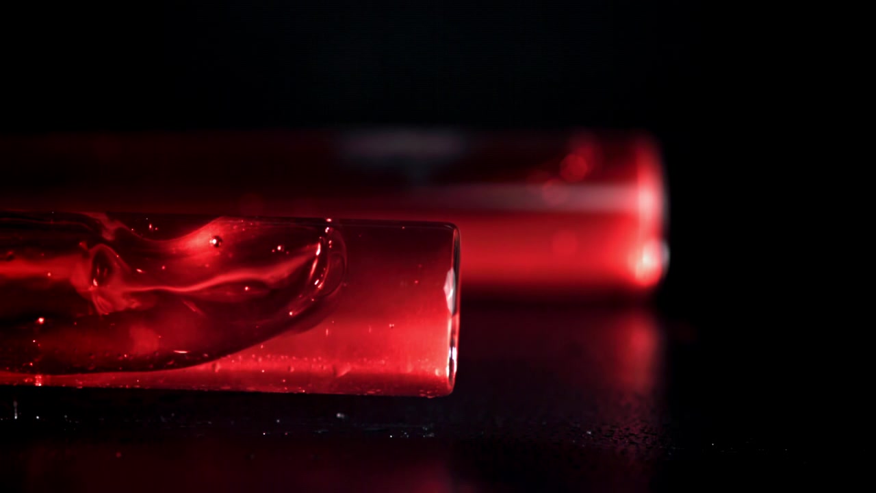 Red Liquid in Test Tube on Dark Surface with Reflections