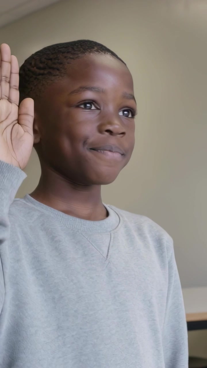 Vertical video: Recording student glancing, smiling and raising hand in class in gray sweatshirt