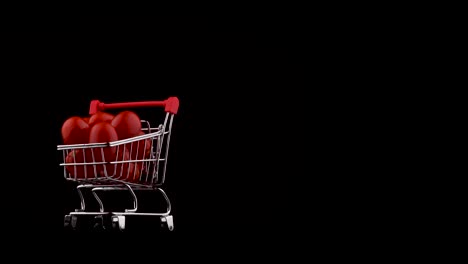 medio marco. disparo macro de un carrito de supermercado lleno de tomates de cereza roja. girando en la mesa giratoria. aislado en el fondo negro. primer plano.