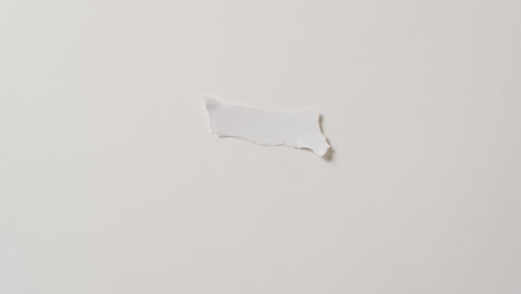 Video-of-close-up-of-torn-piece-of-paper-with-copy-space-on-white-background