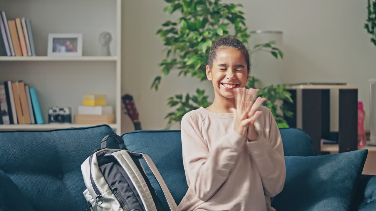 una adolescente negra emocionada volviendo a casa después de la escuela, sonriendo y aplaudiendo
