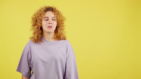 young woman showing surprise and thumbs up on yellow background