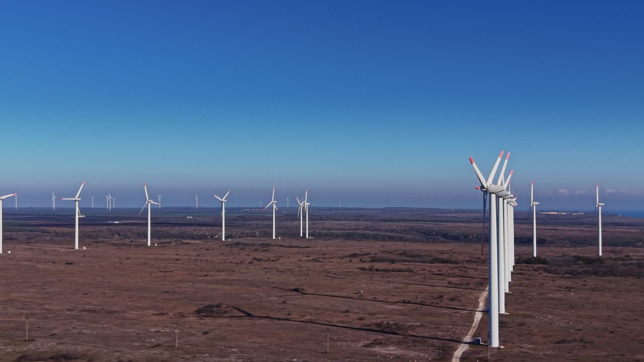As turbinas eólicas se erguem em uma paisagem aberta, em um dia ensolarado e claro em uma área rural