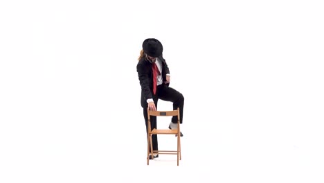 man in suit and hat posing with a chair on white background