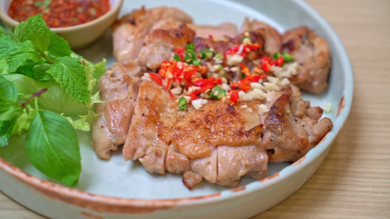 접시에 고추와 마늘을 곁들인 짭짤한 구운 닭고기