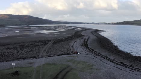 AERIAL---People-and-their-dog-walking-on-Island-Davaar,-Kintyre,-Scotland,-reverse