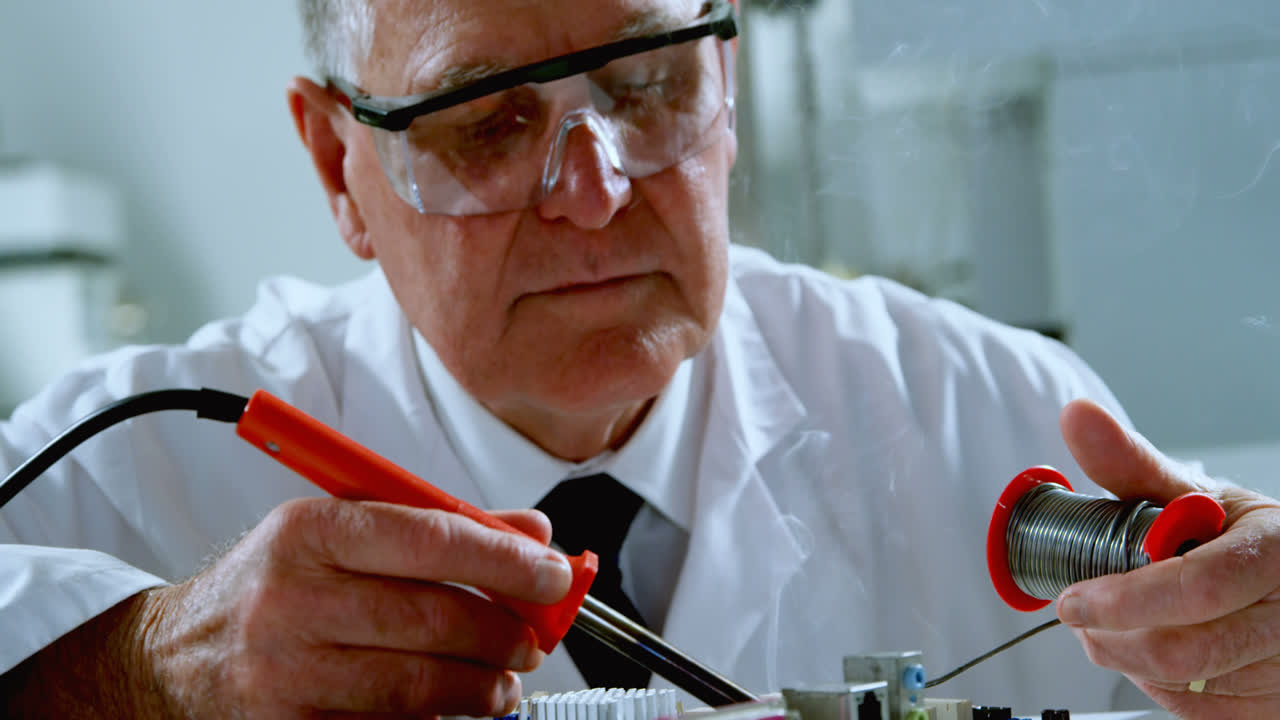 científico masculino soldando una placa de circuito 4k