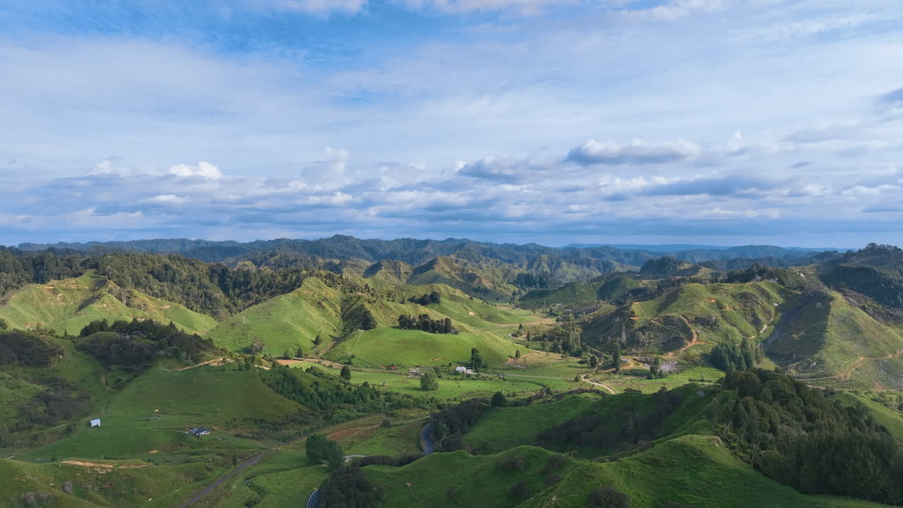 Flight over the quintessential New Zealand hill country landscape, across sharp hills, rich pastures, recovering native forests, towards iconic vacation cottages tucked away in Pohokura Taranaki