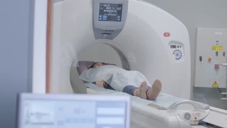 mujer acostada en el escáner de ct o mri durante la máquina de imágenes de su cuerpo, se enciende los rayos infrarrojos y la paciente pasa a través del círculo, grúa disparada de abajo hacia arriba, interior de la habitación, escena activa.