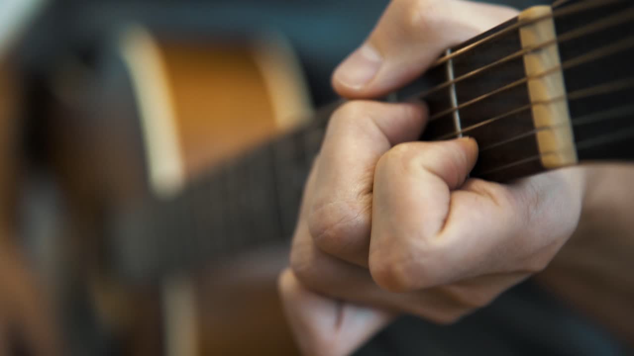 primer plano de 4k de un hombre tocando una guitarra acústica y cambiando acordes rápidamente