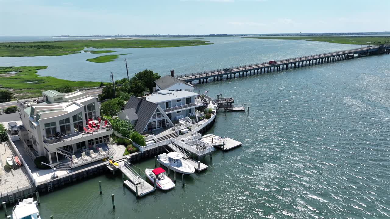 Luxury beach houses with bay view and bridge in stone harbor beach, New Jersey. Sunny day with marshland in background. Private access and jetty with docking boats