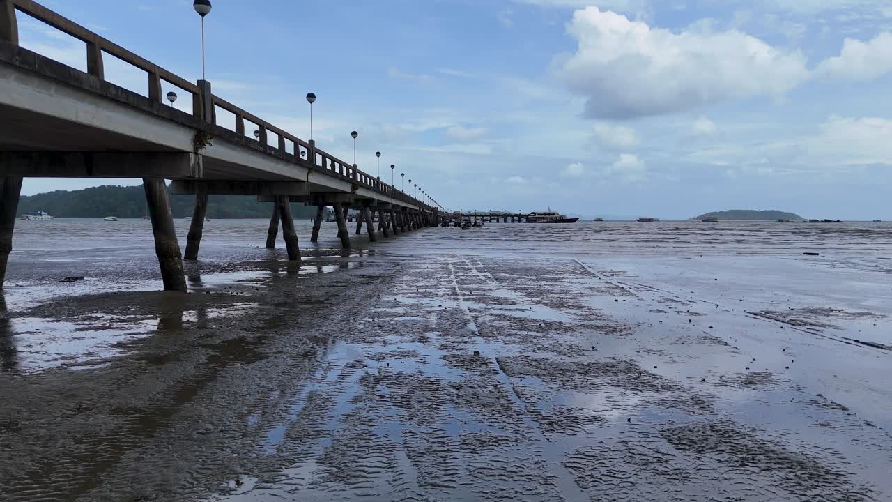 imágenes aéreas capturan un muelle sereno que se extiende en el mar bajo un cielo nublado en phuket, tailandia