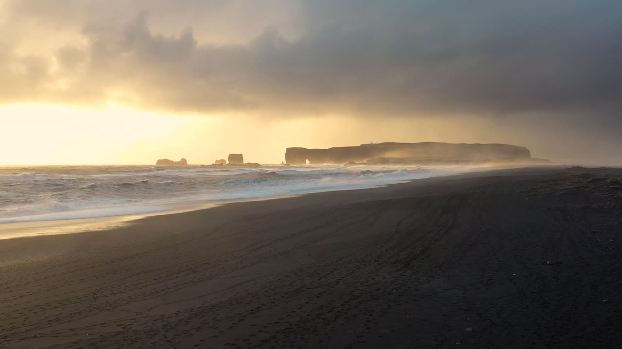Stunning Aerial Footage Capturing Iceland's Black Sand Beach, with Waves Powerfully Crashing Against the Sunset Backdrop