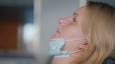 a tired woman with a mask lowered on her chin. sitting in the airport terminal, violating quarantine restrictions