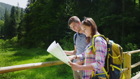 tourism and active lifestyle a young couple looks at the map stand in a picturesque place on a summe