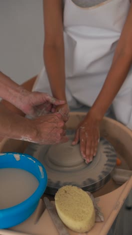 hands shaping clay on a pottery wheel, showing the artistic process and collaborative learning