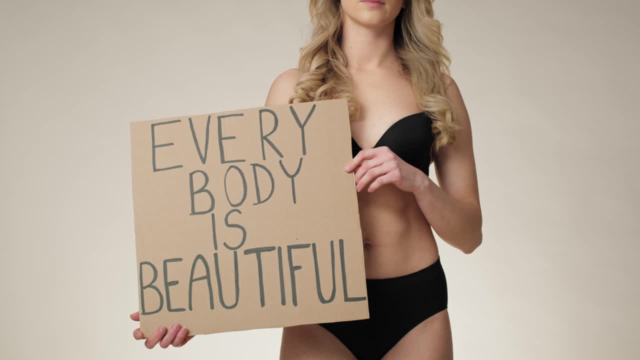 Confident caucasian woman in underwear in the studio holding a banner.