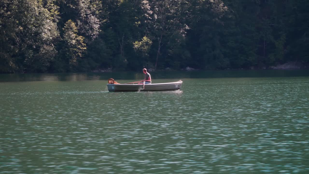 Man rowing boat across the Koenigssee on a beautiful sunny summer day