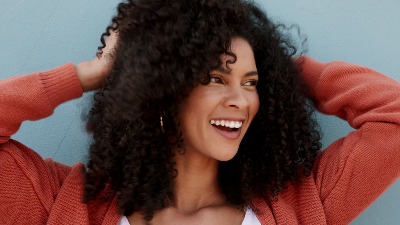 mujer con el cabello rizado usando un cardigan naranja