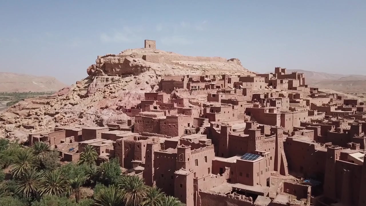 Laaja näkymä Ait Benhaddoun kasbahista, etualalla kuivaa aavikkoa ja sen juurella vihreä keidas Ouarzazatessa. Ikoninen UNESCO-kohde, joka yhdistää kuivan maaston ja perinteisen arkkitehtuurin.