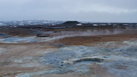 low altitude flight over boiling field of geothermal mud pools and landscape in iceland