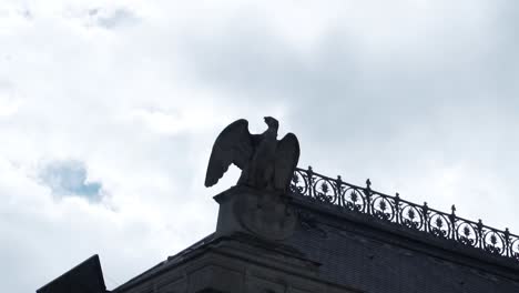 Estatua-De-Pájaro-águila-En-La-Parte-Superior-De-Un-Edificio-Contra-El-Cielo-Nublado-En-París,-Francia