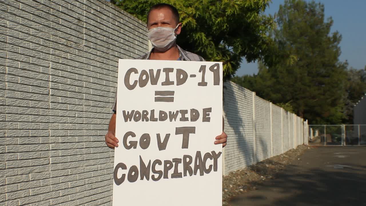 manifestante anti covid con máscara de malla - conspiración mundial