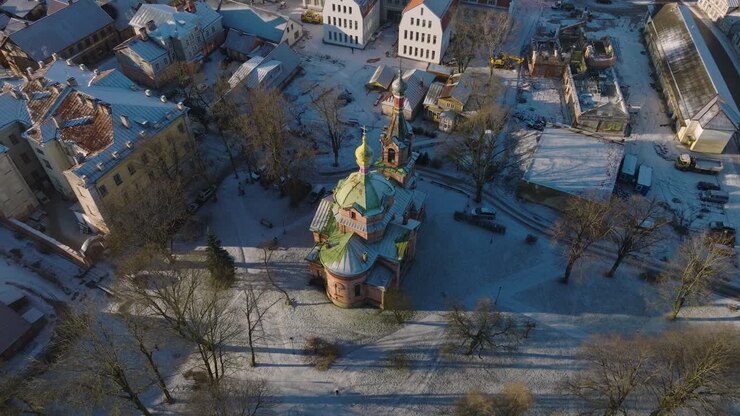 Vue aérienne d'ensemble de la vieille ville de Kuldiga, maisons aux toits de tuiles rouges, église orthodoxe, journée d'hiver ensoleillée, destination de voyage, large plan orbital par drone.