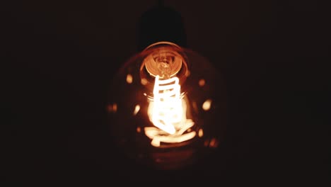 close up shot of old retro vintage light bulb brighten light. tungsten light bulb lamp cozy turn on slowly over black background. comfort cozy, energy, electricity, innovation concept